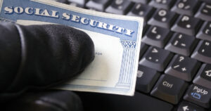 A Thief Holding a Social Security Card Next to a Keyboard