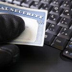 A Thief Holding a Social Security Card Next to a Keyboard