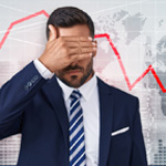 A man covering his eyes as the stock market falls in the background