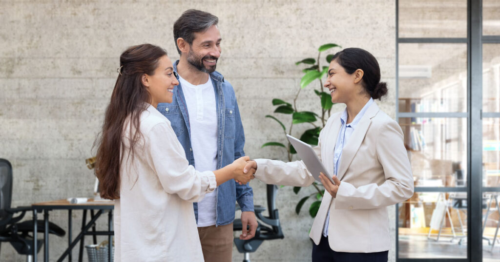A happy couple shaking hands with their advisor