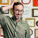 A man thinking in front of a wall of clocks