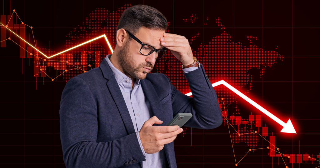 A worried man looking at his phone with a red arrow going down in the background